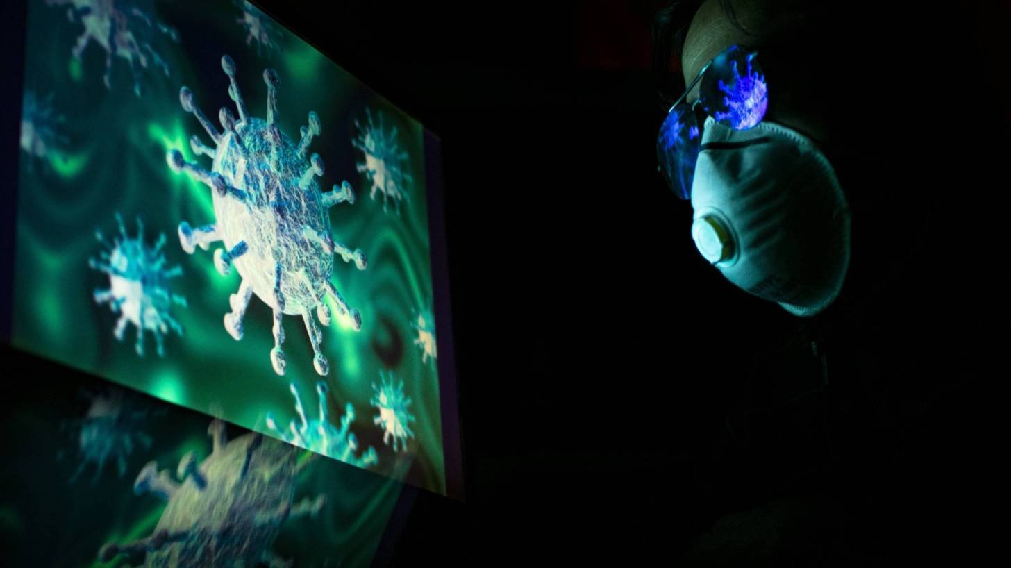 researcher looking at the coronavirus with a mask on