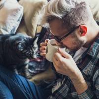 man drinking coffee with his cat