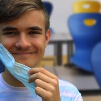 young man smiling take mask off since he is immune to SARS